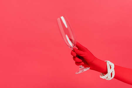 cropped view of woman in glove holding empty champagne glass isolated on redの写真素材