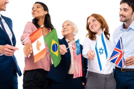Flags of countries in hands of multiethnic businesspeople on burred background isolated on whiteの写真素材