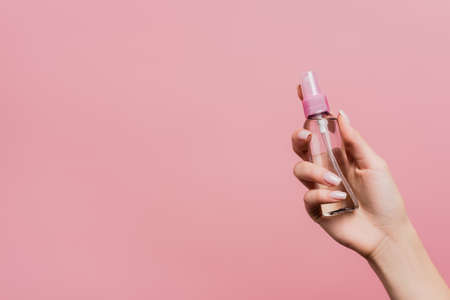 cropped view of woman holding  spray in hand isolated on pinkの写真素材