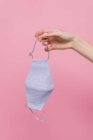 cropped view of woman holding protective cotton mask isolated on pink