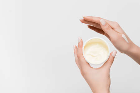 partial view of woman holding container with cosmetic cream isolated on whiteの写真素材