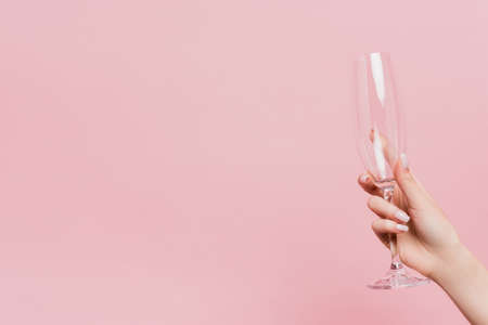 cropped view of woman holding empty champagne glass isolated on pinkの写真素材