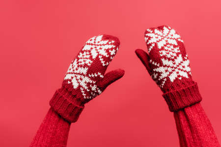 cropped view of female hands in warm mittens isolated on redの写真素材