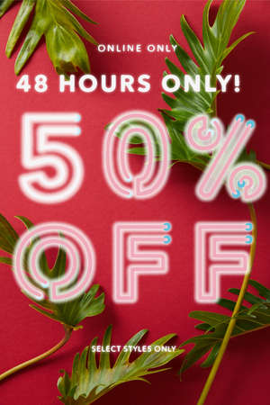 top view of tropical green leaves on red background with sale illustration