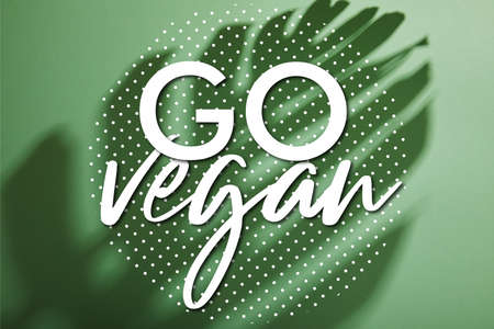 tropical leaf shadow on green background with go vegan illustrationの写真素材