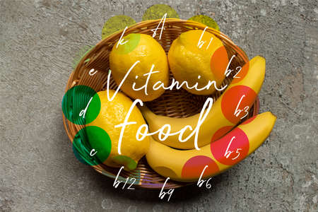 top view of colorful bananas and lemons in wicker basket on gray concrete surface, vitamin food illustrationの写真素材