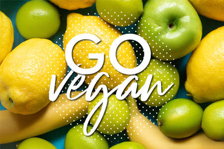 top view of yellow lemons, bananas, green apples and limes, go vegan illustrationの写真素材