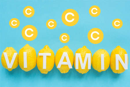 top view of ripe yellow lemons and vitamin C illustration on blue backgroundの写真素材