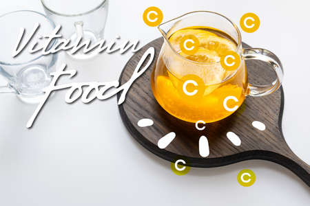 hot tea in teapot with lemon and ginger on wooden board near empty cups on white background, vitamin...