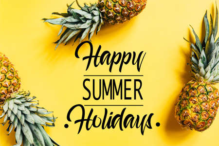 top view of fresh tasty pineapples on yellow background with happy summer holidays illustrationの写真素材