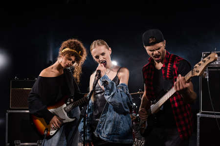 KYIV, UKRAINE - AUGUST 25, 2020: Blonde vocalist of rock band singing near musicians with bass...