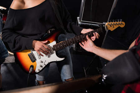KYIV, UKRAINE - AUGUST 25, 2020: Cropped view of man touching guitar strings, while woman playing during rock band rehearsalのeditorial素材