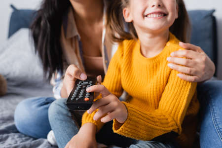 cropped view of happy child watching tv with mother on blurred backgroundの写真素材