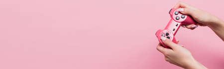 KYIV, UKRAINE - OCTOBER 26, 2020: partial view of woman holding joystick isolated on pink, banner