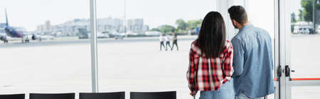 back view of couple standing with luggage in departure lounge of airport, bannerの写真素材