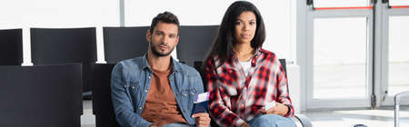 interracial passengers holding passports with air tickets in airport, banner