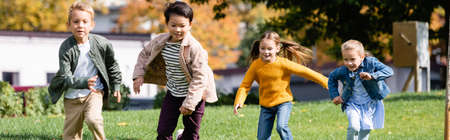 Cheerful multicultural children running in park, banner