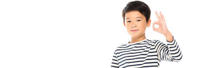 Asian schoolboy showing okay gesture and looking at camera isolated on white, bannerの写真素材