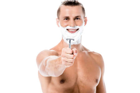smiling sexy shirtless man with foam on face holding razor isolated on whiteの写真素材