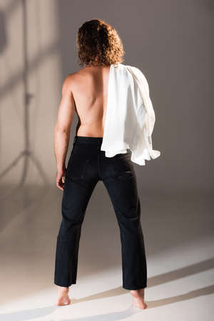back view of sexy shirtless man with long hair posing on dark backgroundの写真素材