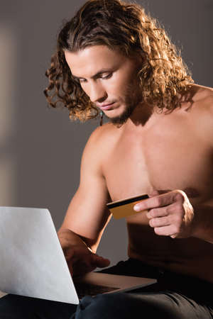 sexy shirtless man holding laptop and credit cardの写真素材