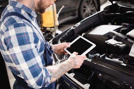 cropped view of technician holding digital tablet near car engine compartmentの写真素材
