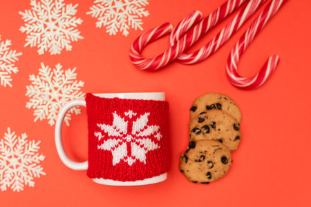 top view of chocolate cookies, candy canes, snowflakes and mug on red backgroundの写真素材