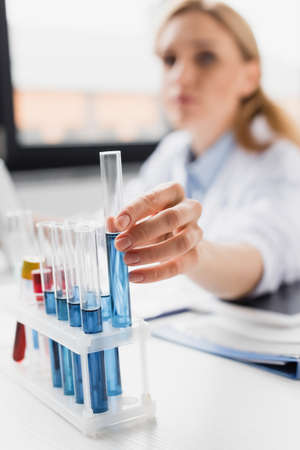 test tube with blur liquid in hand of doctor on blurred background