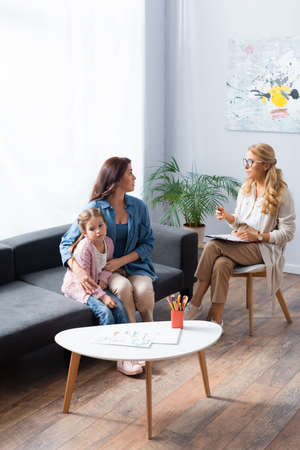 mother hugging daughter while visiting psychologistの写真素材