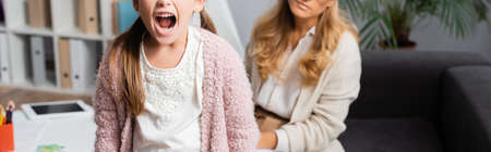 cropped view of angry little girl screaming while visiting psychologist, banner