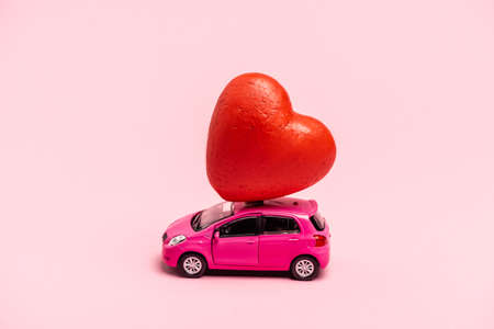 toy car and red heart on pink backgroundの写真素材