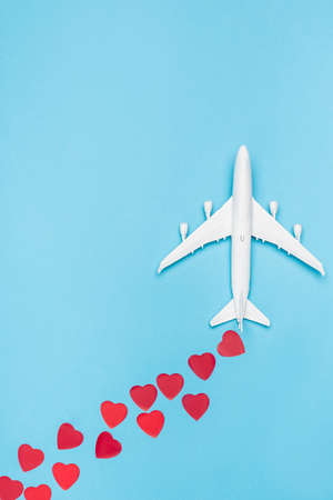top view of plane model and red hearts on blue background