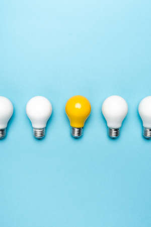 top view of white and yellow light bulbs on blue backgroundの写真素材