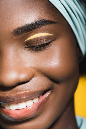 closeup of smiling african american young woman isolated on yellow