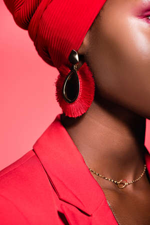 closeup of african american young woman in earring isolated on redの写真素材