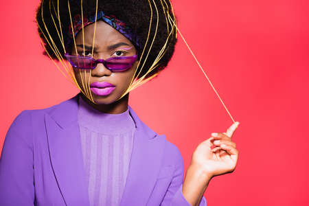 african american young woman in purple stylish outfit and sunglasses with yellow strings on face...