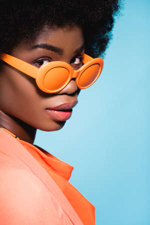 african american young woman in orange stylish outfit isolated on blue backgroundの写真素材
