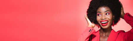 happy african american young woman in stylish outfit isolated on red, banner