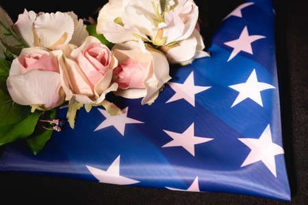 rose bouquet and american flag on black background, funeral concept