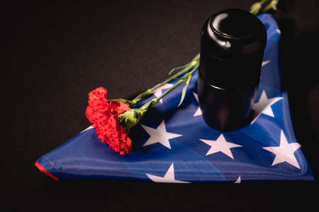 red carnation, ashes and american flag on black background, funeral conceptの写真素材