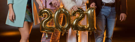 cropped view of friends holding 2021 numbers balloons on black, bannerの写真素材
