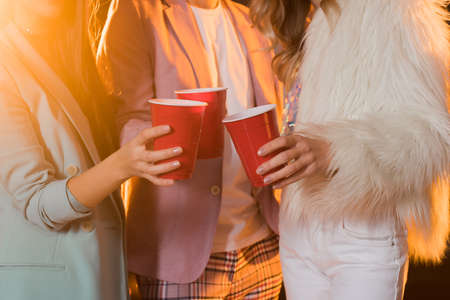 cropped view of man and women toasting plastic cups during party on blackの写真素材