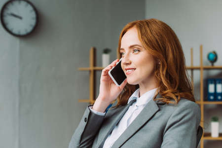 Smiling female lawyer talking on mobile phone and looking away on blurred backgroundの写真素材