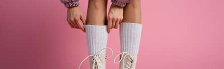 cropped view of female legs in boots and socks on pink background, bannerの写真素材