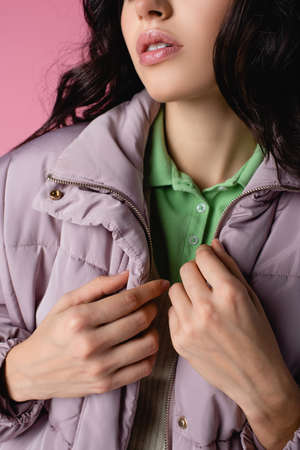 cropped view of young woman in stylish puffer jacket on pink background