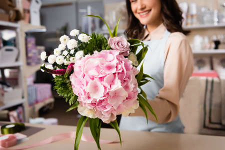 Close up view of bouquet in hand of female florist on blurred background
