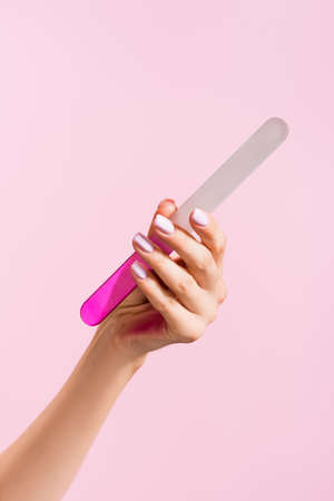 cropped view of woman holding nail file isolated on pinkの写真素材
