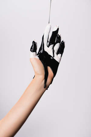 cropped view of hand with dripping black paint isolated on white