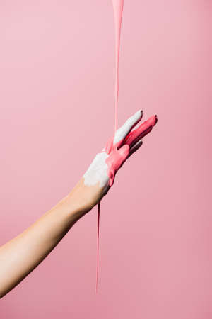 cropped view of hand with dripping paint isolated on pinkの写真素材