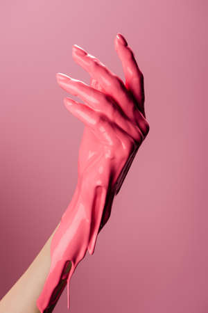 cropped view of hand with dripping paint isolated on pinkの写真素材